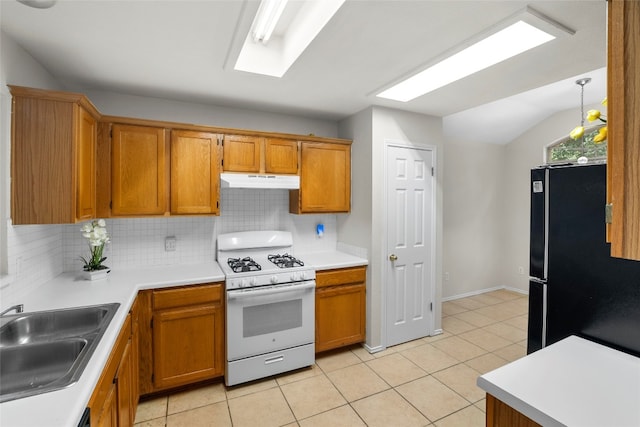 kitchen with backsplash, black fridge, vaulted ceiling, gas range gas stove, and sink