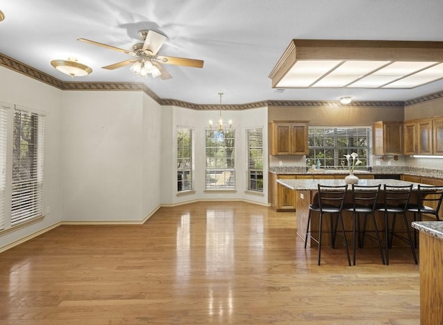300 Delaware Springs Blvd, Burnet, TX 78611 - kitchen featuring brown cabinetry, a breakfast bar, a chandelier, light wood finished floors, and ceiling fan