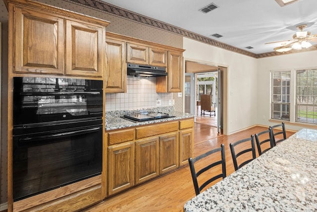 kitchen featuring light hardwood / wood-style floors, tasteful backsplash, black appliances, and a wealth of natural light