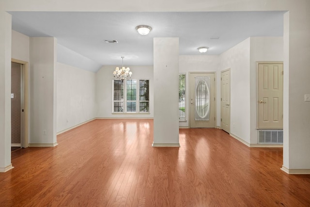 entrance foyer featuring lofted ceiling, a notable chandelier, and light hardwood / wood-style floors