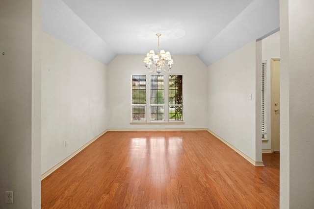 unfurnished room with light hardwood / wood-style floors, an inviting chandelier, and vaulted ceiling