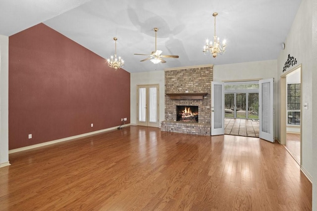 300 Delaware Springs Blvd, Burnet, TX 78611 - unfurnished living room featuring a chandelier, ceiling fan, a fireplace, wood finished floors, and high vaulted ceiling