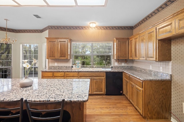 kitchen with a kitchen breakfast bar, light stone countertops, dishwasher, light hardwood / wood-style floors, and sink