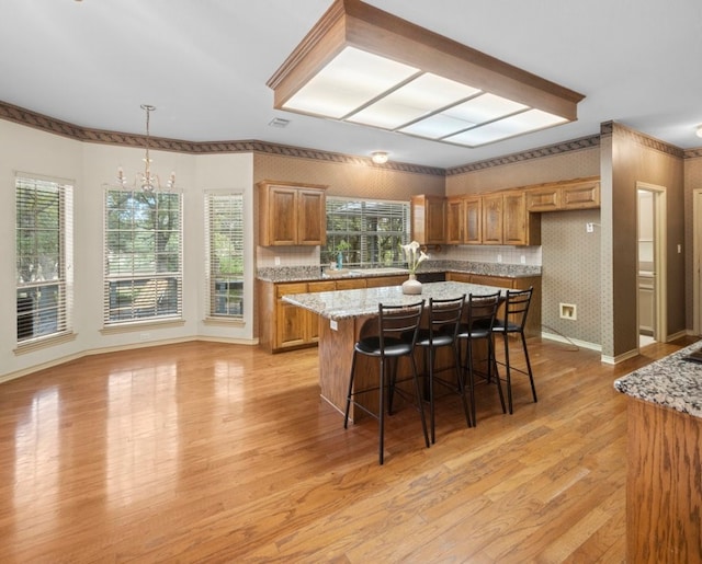 kitchen featuring a breakfast bar, light stone counters, light hardwood / wood-style flooring, and a chandelier