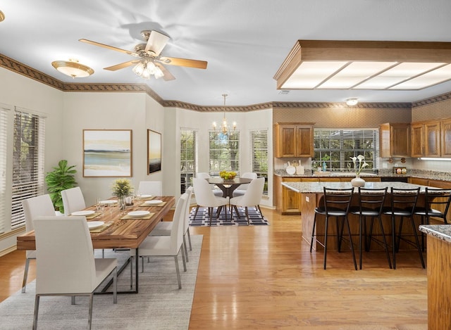 dining space with ceiling fan, ornamental molding, and light wood-type flooring