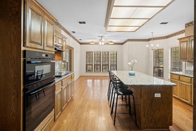 kitchen featuring light hardwood / wood-style flooring, black appliances, a kitchen island, and a wealth of natural light