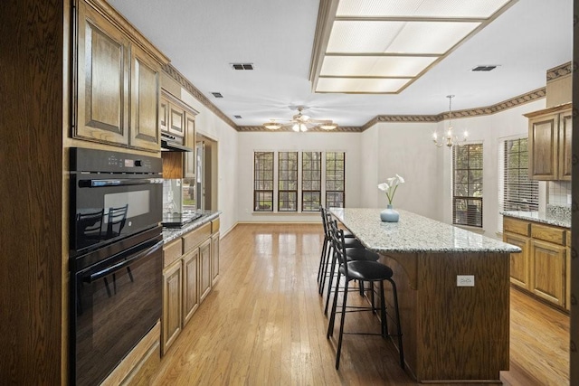 300 Delaware Springs Blvd, Burnet, TX 78611 - kitchen with light wood-type flooring, a breakfast bar area, a chandelier, a center island, and a ceiling fan