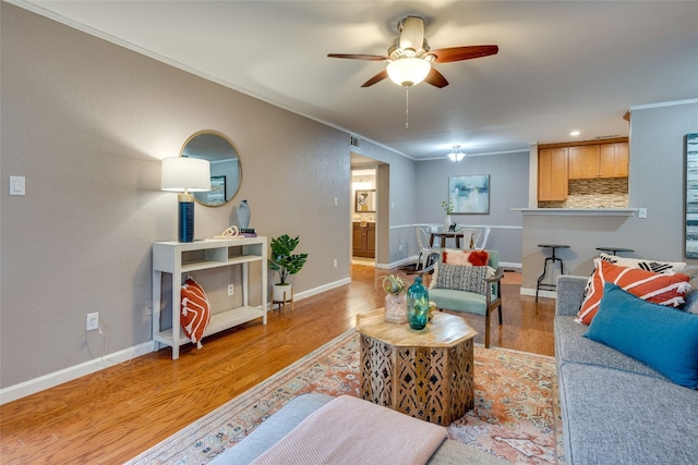 living room with ornamental molding, light wood-type flooring, and ceiling fan