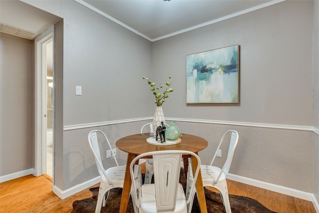 dining space with crown molding and hardwood / wood-style flooring