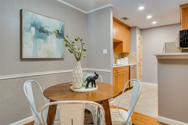 dining space with light tile patterned flooring, crown molding, and sink