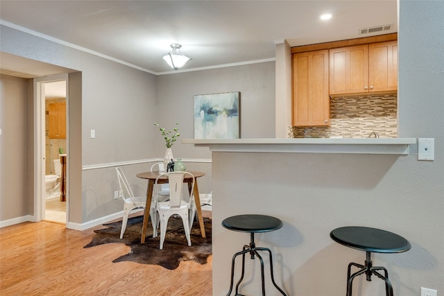 dining room with crown molding and light hardwood / wood-style flooring