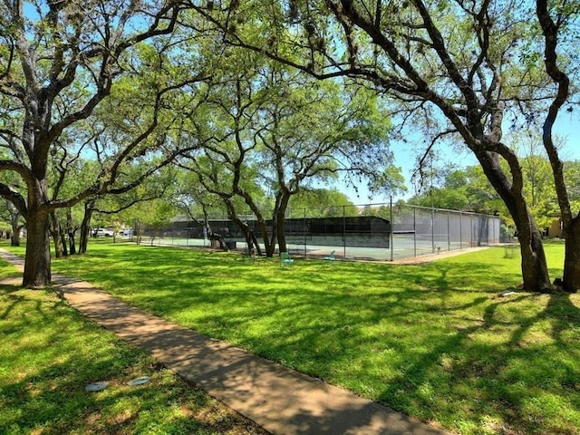 view of property's community with a lawn and tennis court