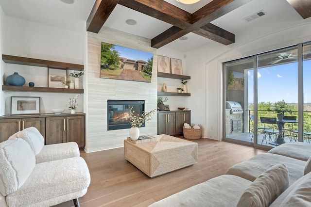 living room with coffered ceiling, beamed ceiling, light hardwood / wood-style flooring, and a fireplace