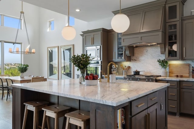 kitchen with appliances with stainless steel finishes, light hardwood / wood-style flooring, tasteful backsplash, and pendant lighting