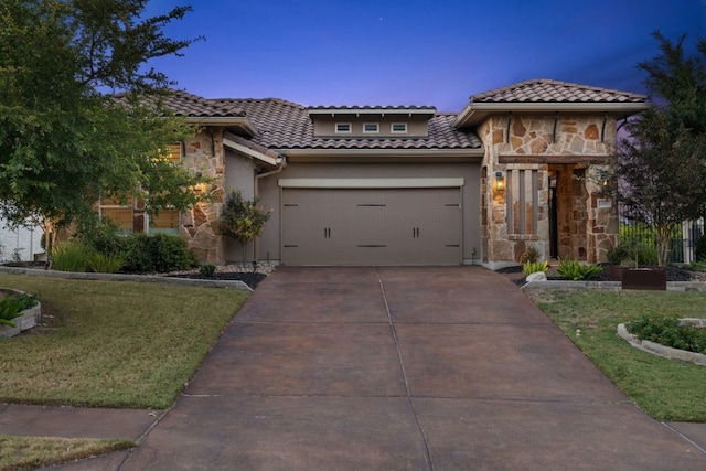 mediterranean / spanish home featuring a garage and a front lawn