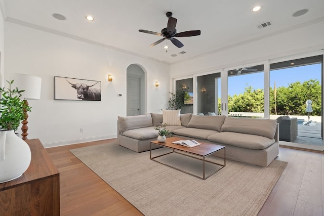 living room featuring light hardwood / wood-style flooring, ceiling fan, and crown molding