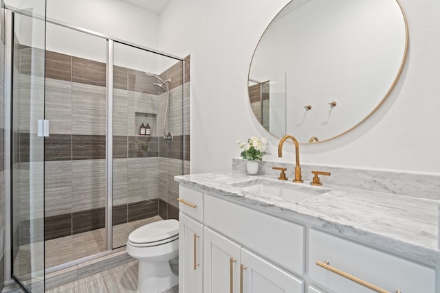 bathroom with toilet, a shower with shower door, and vanity