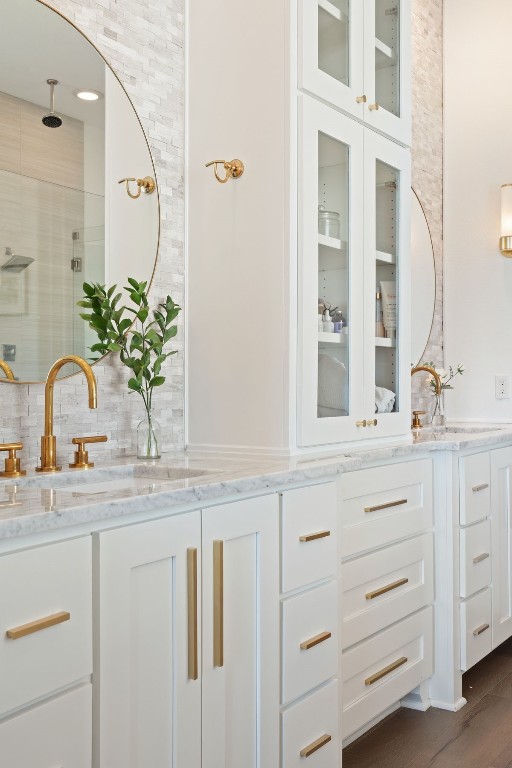 bathroom featuring hardwood / wood-style floors, vanity, a shower, and decorative backsplash