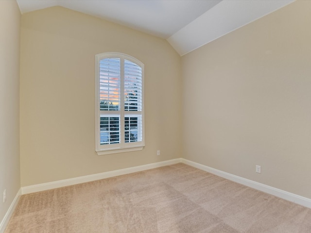 carpeted empty room featuring vaulted ceiling