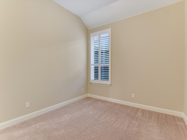 empty room with vaulted ceiling and light colored carpet