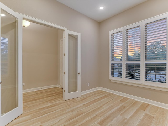 unfurnished bedroom with french doors and light wood-type flooring