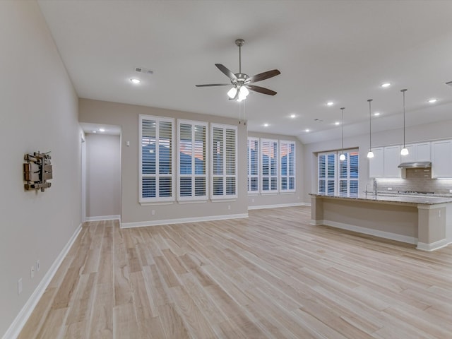 unfurnished living room with sink, light hardwood / wood-style flooring, and ceiling fan