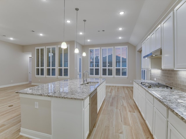 kitchen with a large island with sink, sink, white cabinetry, and tasteful backsplash