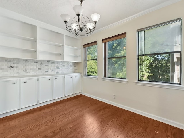 unfurnished dining area with an inviting chandelier, dark wood-type flooring, and crown molding