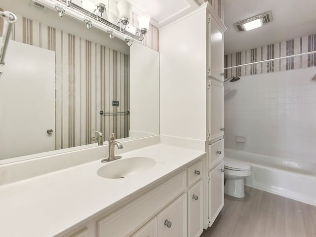 full bathroom with vanity, tiled shower / bath combo, wood-type flooring, and toilet