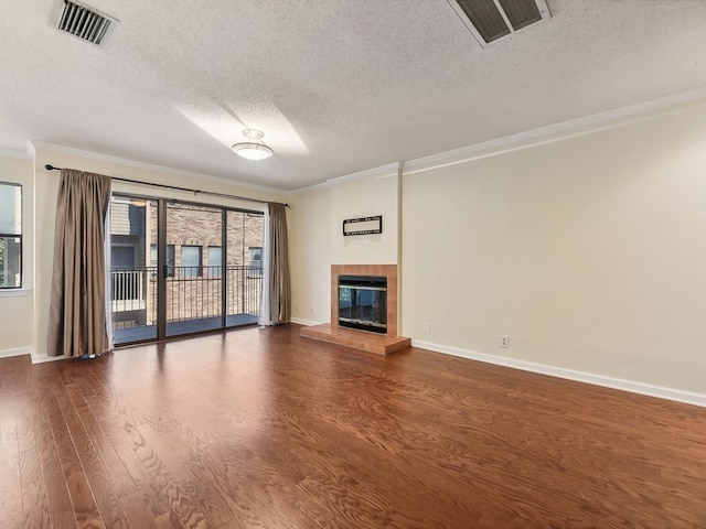 unfurnished living room featuring ornamental molding, a textured ceiling, a tile fireplace, and dark hardwood / wood-style flooring