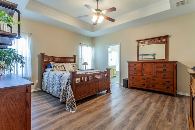 bedroom with multiple windows, dark wood-type flooring, and a raised ceiling