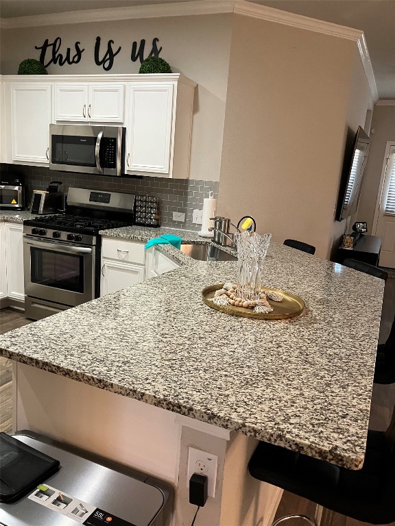 kitchen featuring white cabinets, stainless steel appliances, tasteful backsplash, and a kitchen breakfast bar