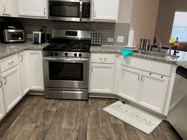 kitchen with dark wood-type flooring, sink, white cabinets, appliances with stainless steel finishes, and light stone counters