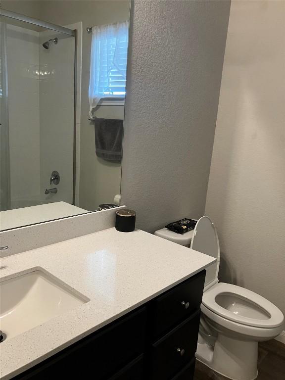 13708 Cantarra Dr, Pflugerville, TX 78660 - full bath featuring a shower with shower door, toilet, a textured wall, and vanity
