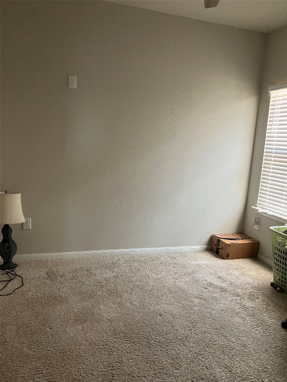 carpeted spare room featuring ceiling fan