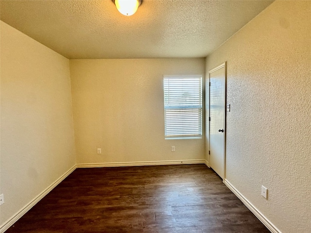 unfurnished room featuring dark wood-type flooring and a textured ceiling