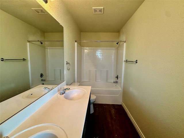 full bathroom with hardwood / wood-style flooring, toilet, bathtub / shower combination, vanity, and a textured ceiling