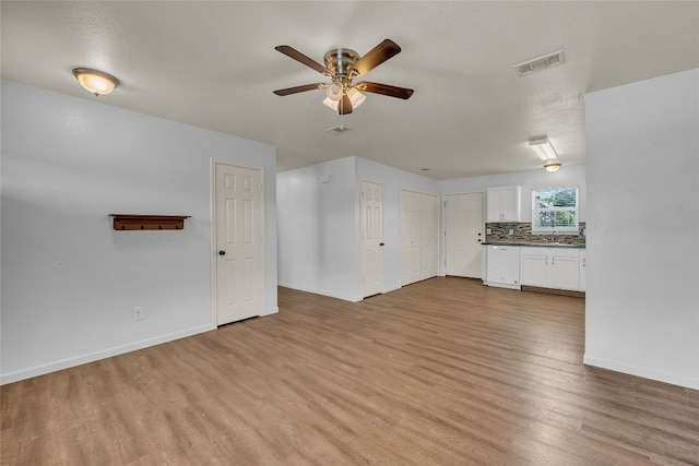 unfurnished living room featuring light hardwood / wood-style flooring, a textured ceiling, sink, and ceiling fan