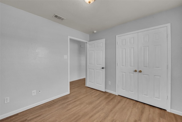 unfurnished bedroom with a closet and light wood-type flooring