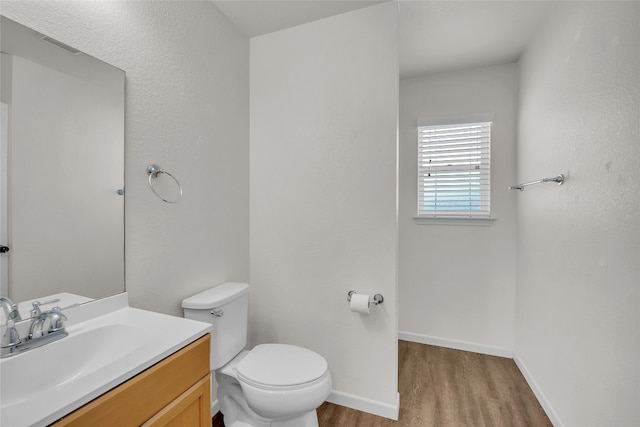 bathroom with toilet, hardwood / wood-style floors, and vanity