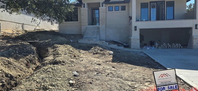 view of side of home with driveway and stone siding