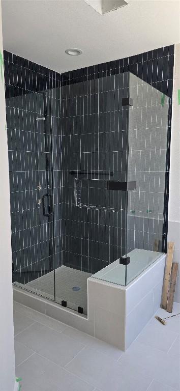 bathroom with a stall shower and tile patterned floors