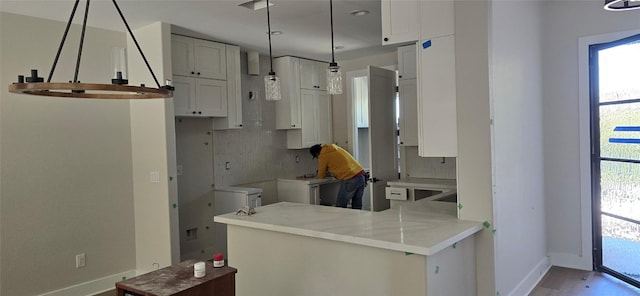 kitchen with pendant lighting, decorative backsplash, white cabinetry, a peninsula, and baseboards