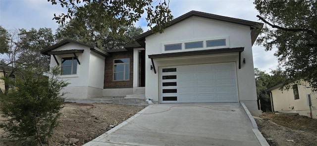 view of front of house featuring concrete driveway, an attached garage, and stucco siding