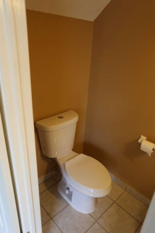 bathroom featuring toilet, tile patterned floors, and a textured ceiling