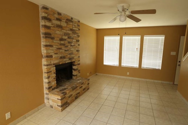 unfurnished living room featuring ceiling fan, a stone fireplace, and light tile patterned floors