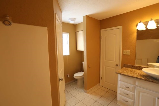 bathroom with vanity, toilet, a textured ceiling, and tile patterned flooring