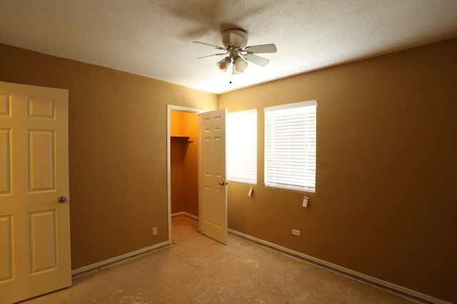 unfurnished bedroom with a closet, a textured ceiling, a spacious closet, and ceiling fan