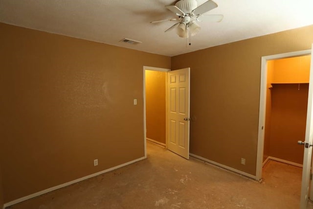 unfurnished bedroom featuring a spacious closet, a closet, and ceiling fan