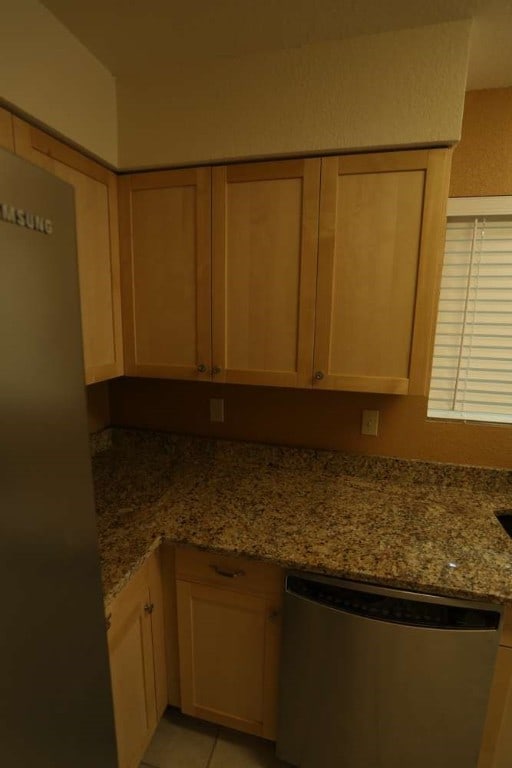 kitchen with light brown cabinets, dishwasher, and light stone countertops